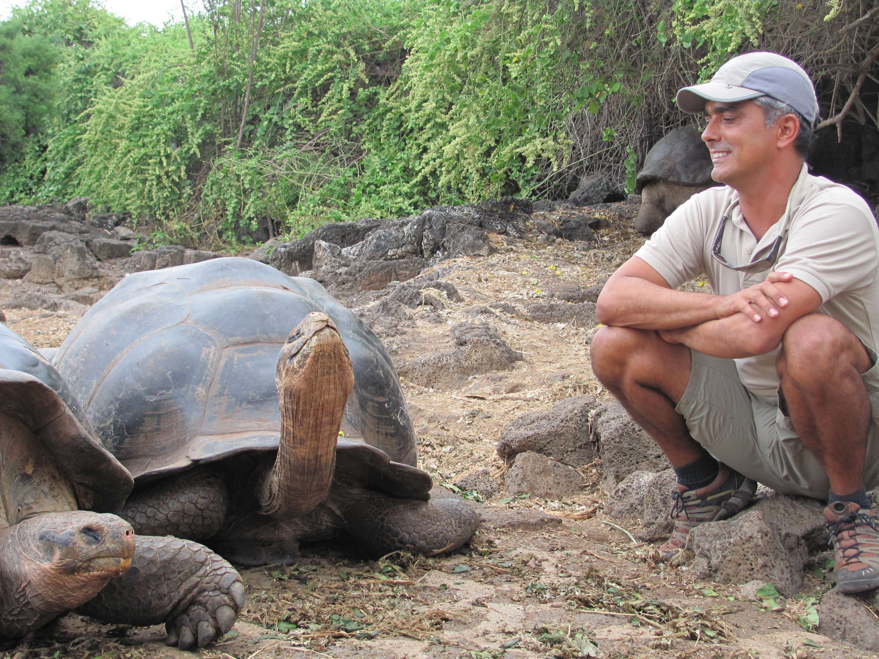 Expedition Leader, Roberto Plaza, enjoying a moment with the island's eponymous giant tortoise.© Holly Glessner/NHA