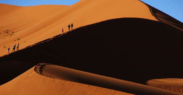 Travelers on a san dune in Namibia. 