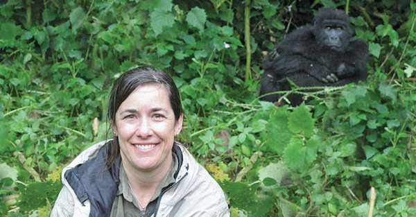 Natural Habitat Adventures traveler posing with a gorilla, Bwindi Impenetrable National Park, Uganda.