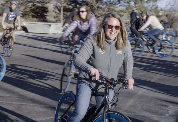 Shelby Campbell, Adventure Relations Director, joyfully rides her bike in the NHA parking lot.