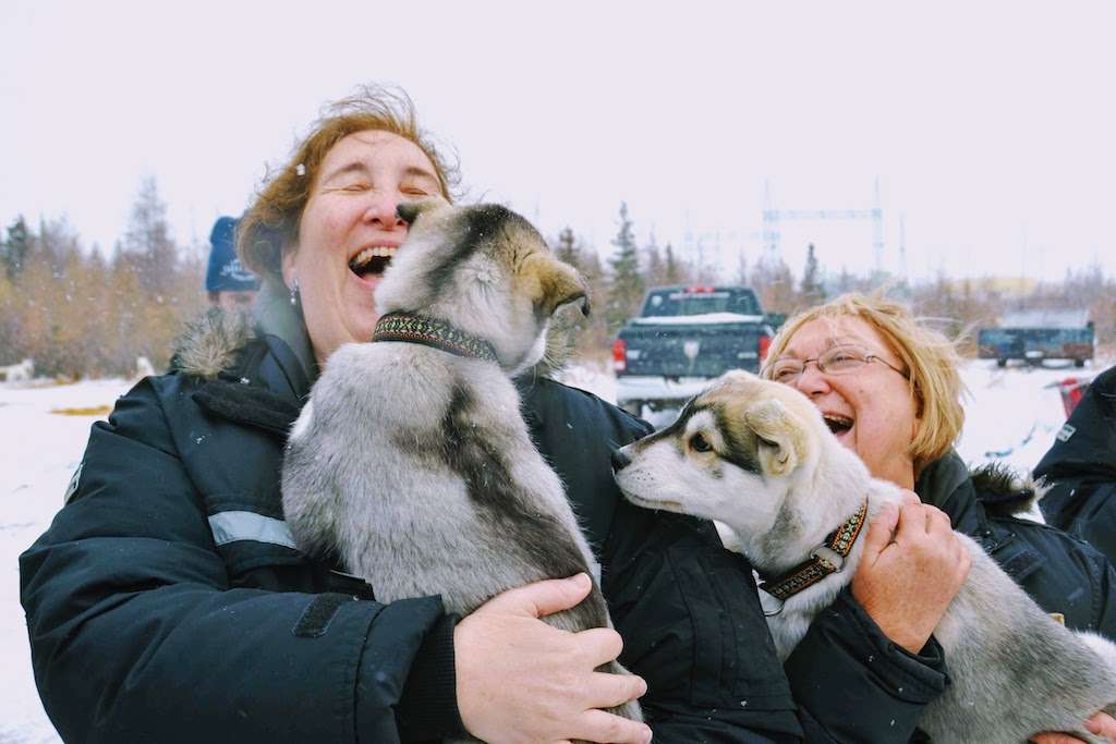 Nat Hab travelers snuggle with husky puppies before dogsledding in Churchill. 