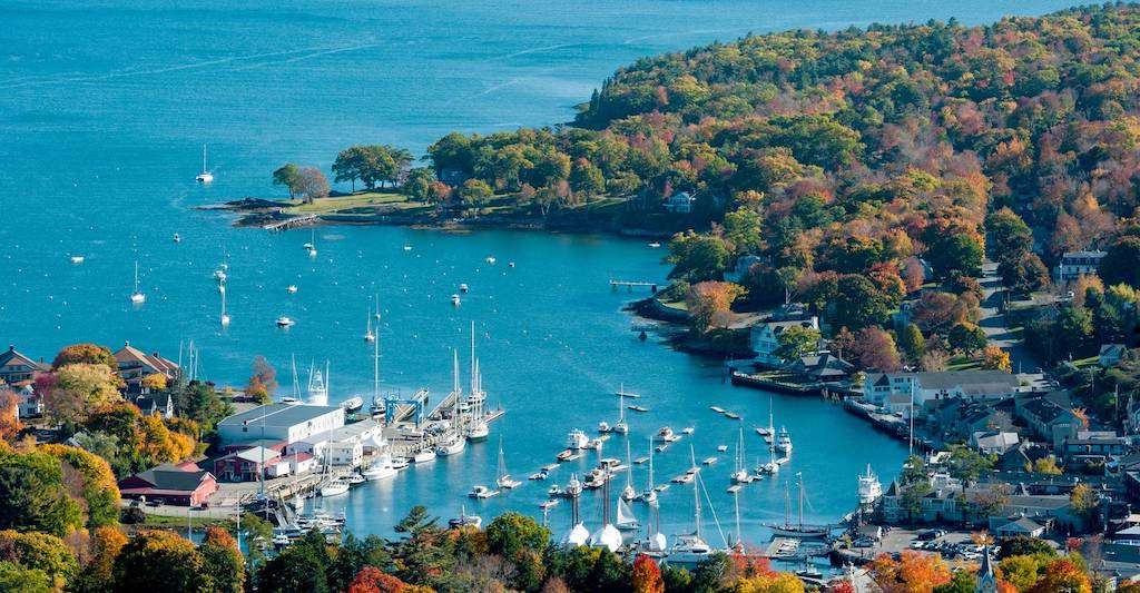 Camden, Maine harbor nestled in amid fall foliage. 