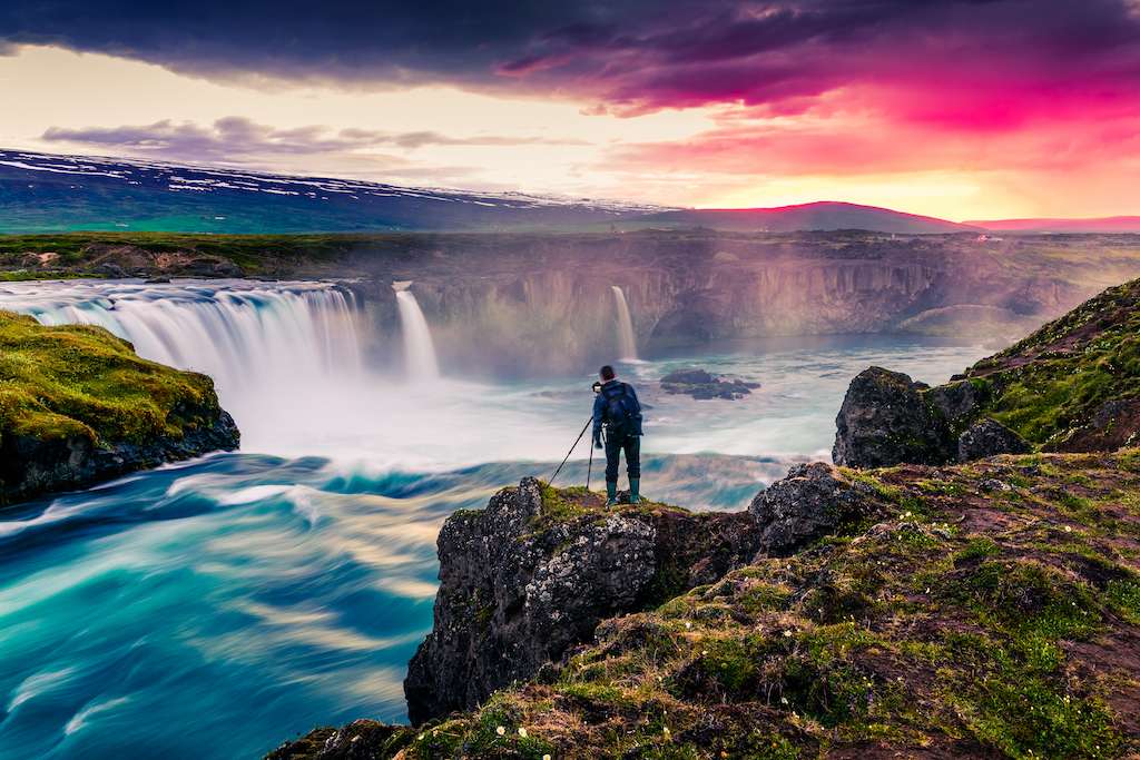 Summer morning scene at Godafoss Waterfall with a photographer. 