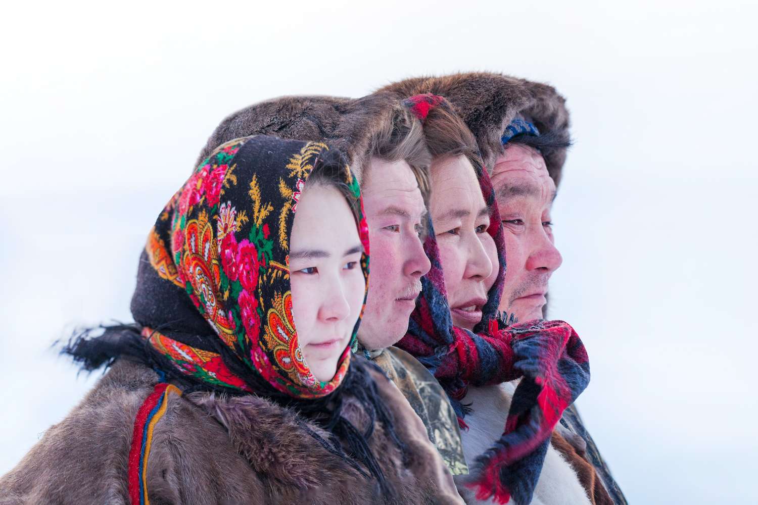 Big family in the national winter clothes of the northern inhabitants of the tundra, the Arctic circle, ethnic Nenets. Portrait of people in profile all together.