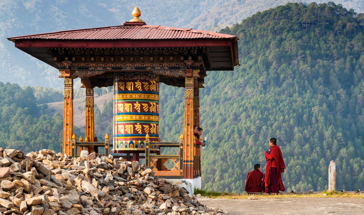 Punakha/Bhutan - March 1, 2016: young women monks of the Buddhist monastery in their traditional red robes before classes next to the prayer wheel against the background of the Himalayan mountains