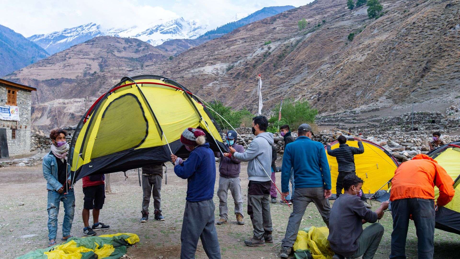 Expedition team members set up camp for the day after a grueling day of trekking across the mountains.