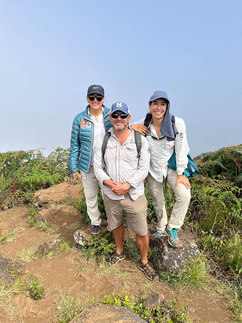 Three Nat Hab guides smiling on verdant island in Galapagos 