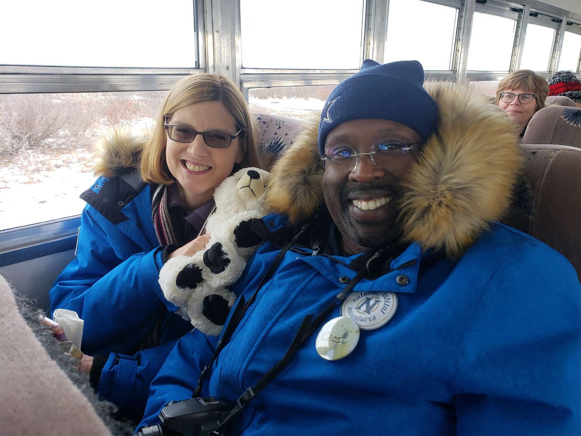 Viajeros sonriendo y sosteniendo un oso polar de peluche de WWF en Churchill 
