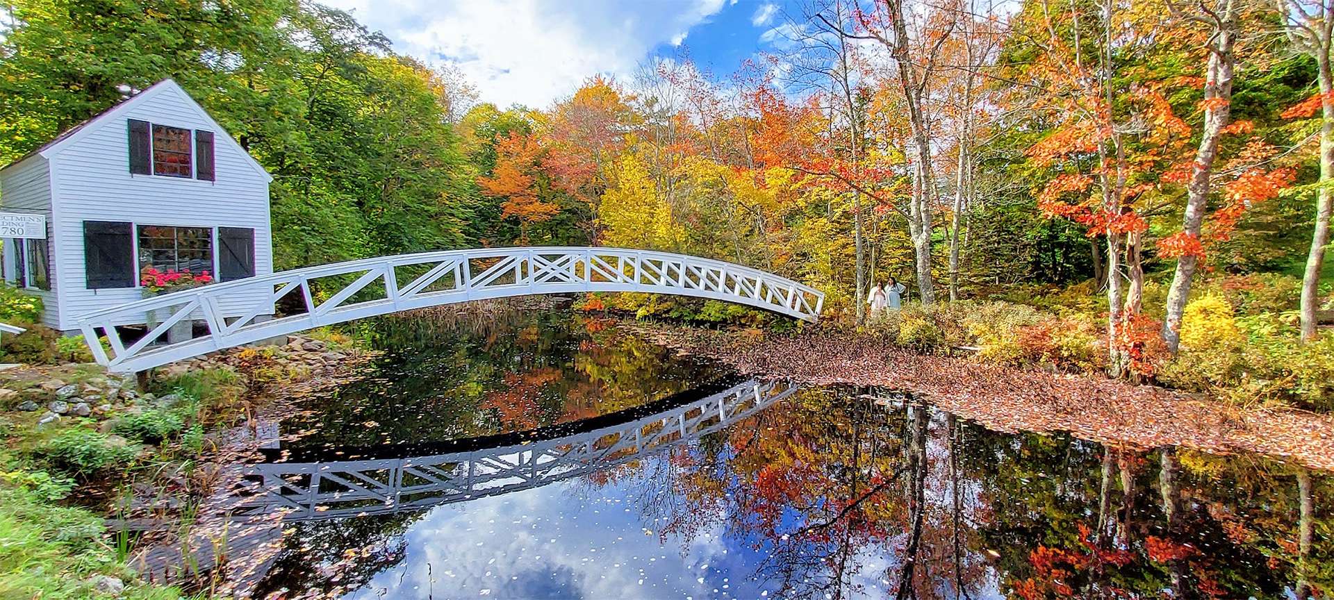 Maine, explorador costero, follaje de otoño, puente blanco y cabaña sobre un arroyo con árboles rojos, anaranjados y amarillos, zen pacífico 