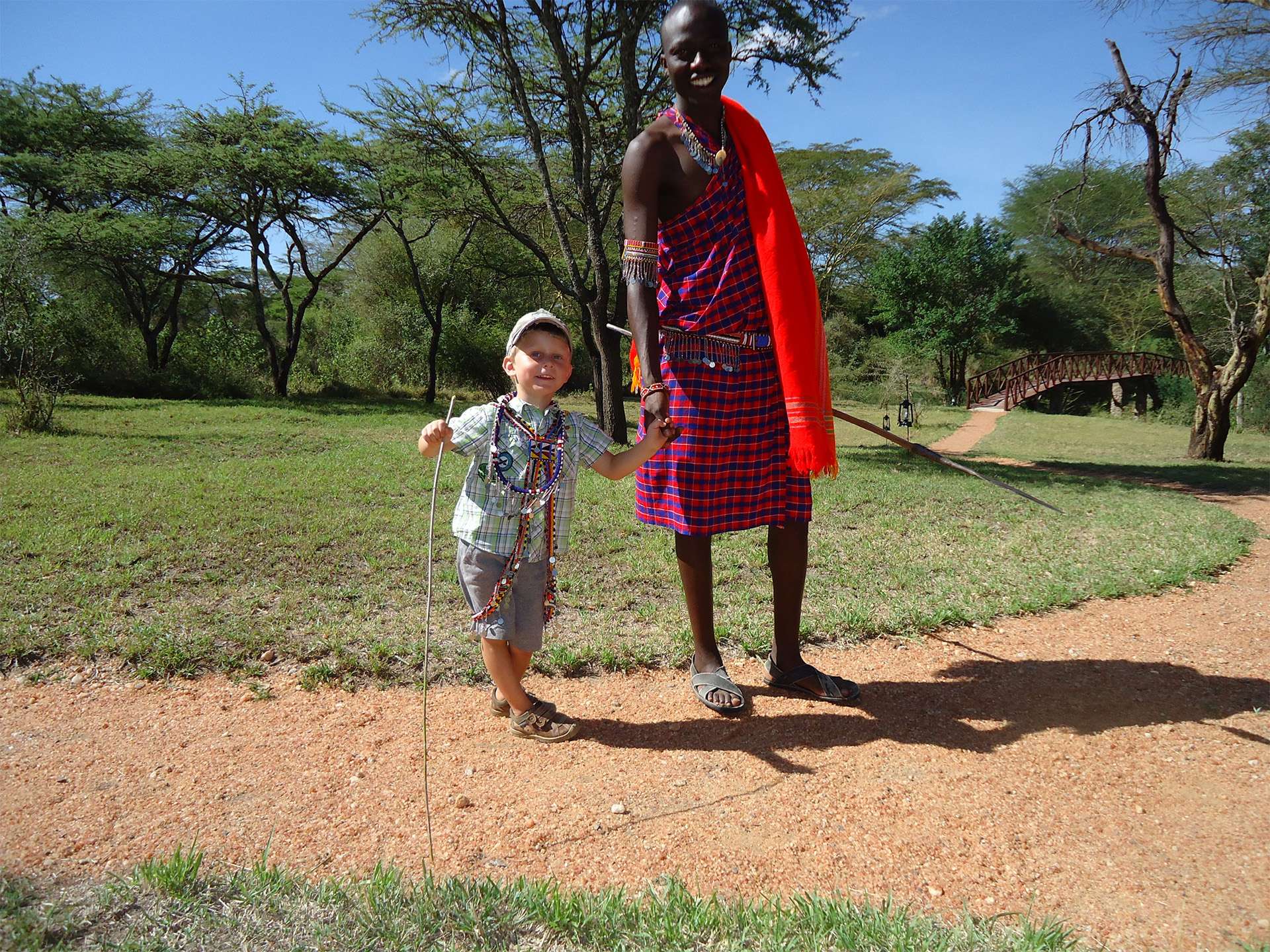 Chico de la tribu masai de Kenia tomados de la mano con el hombre masai 