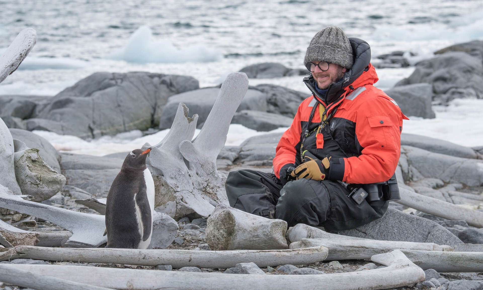 Man with penguin in Antarctica by Colby Brokvist