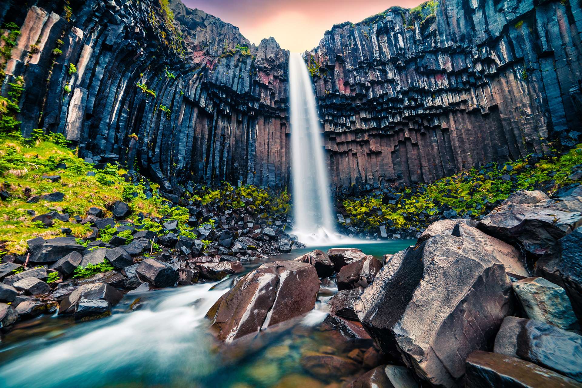 Dramatic morning view of famous Svartifoss (Black Fall) Waterfall. Colorful summer sunrise in Skaftafell, Vatnajokull National Park, Iceland, Europe. Artistic style post processed photo.