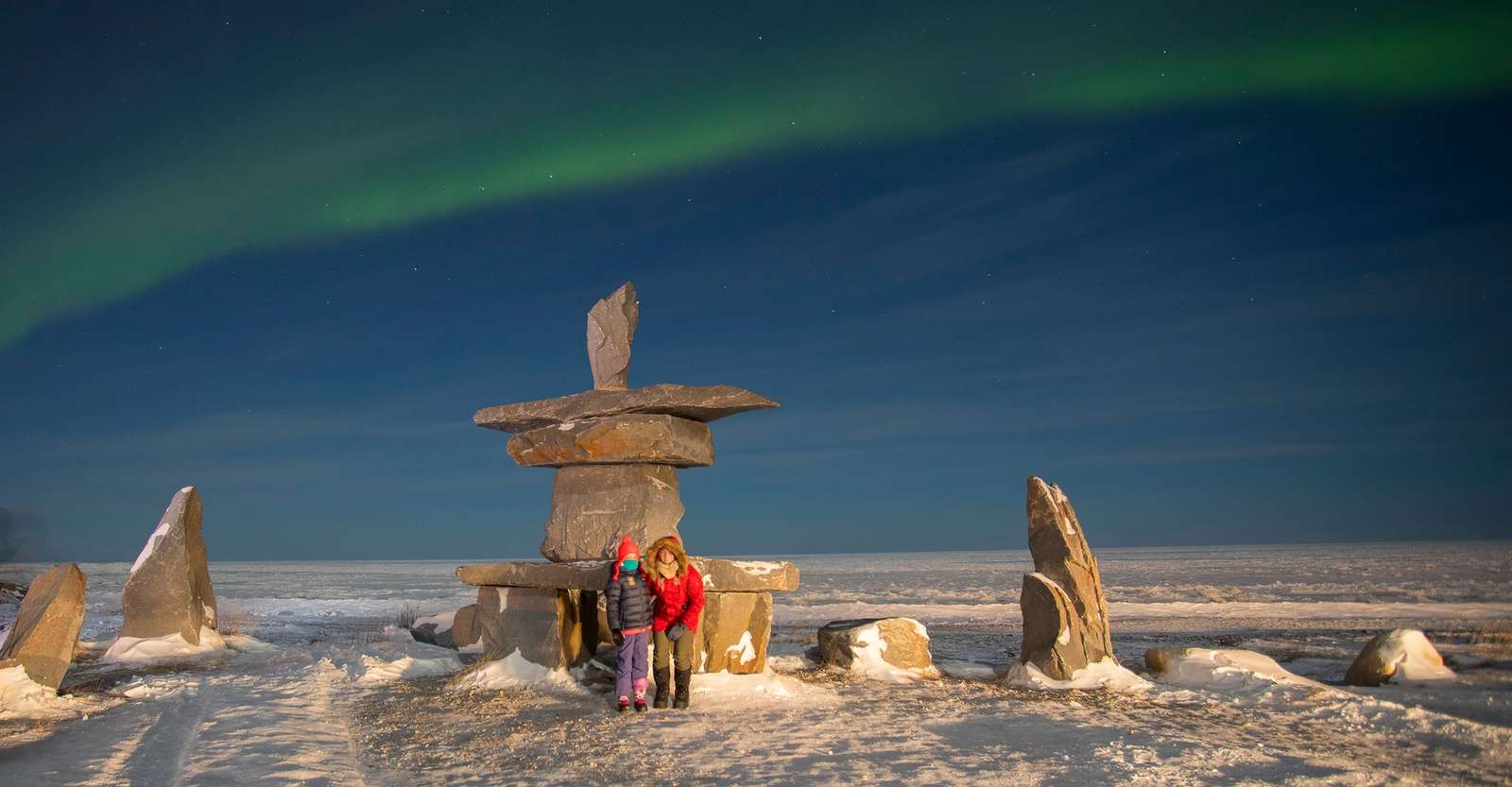 Nat Hab guests in front of Inukshuk and northern lights, Churchill, Manitoba.