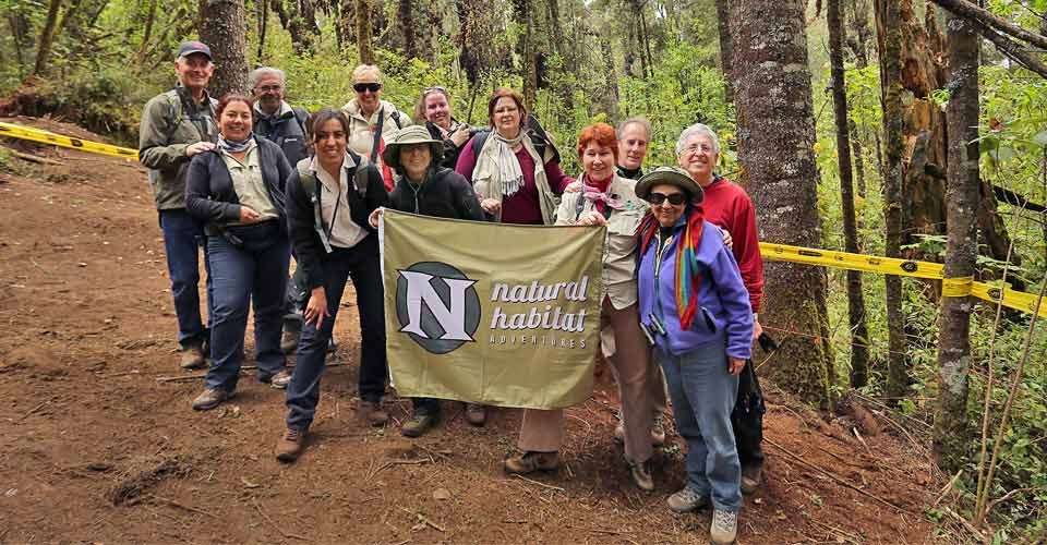 Nat Hab guests holding Nat Hab flag, El Rosario Butterfly Sanctuary, Mexico.