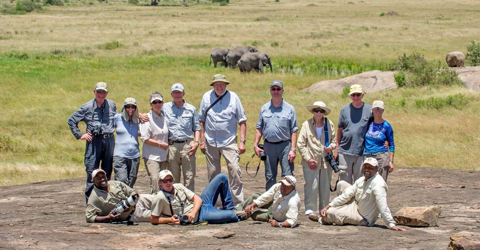 Nat Hab guests and Expedition Leaders pose in front of elephants, Ngorongoro Crater, Tanzania.