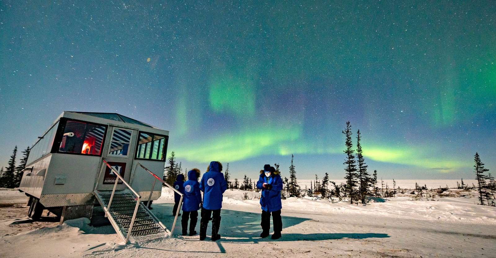 Travelers viewing northern lights outside Nat Hab