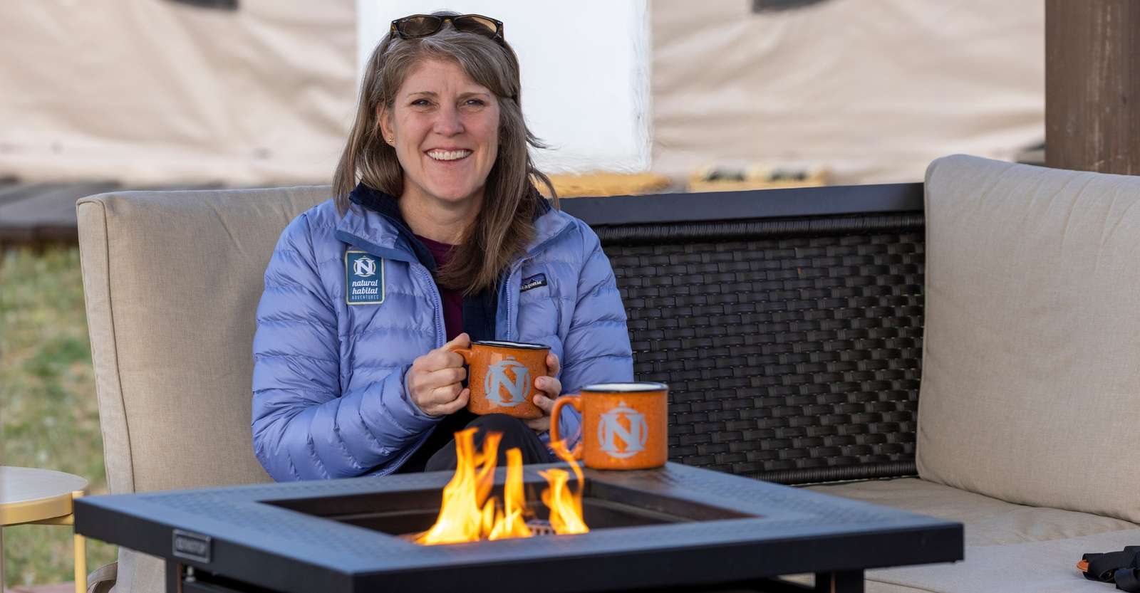 Traveler enjoying a warm drink and a fire at Nat Hab