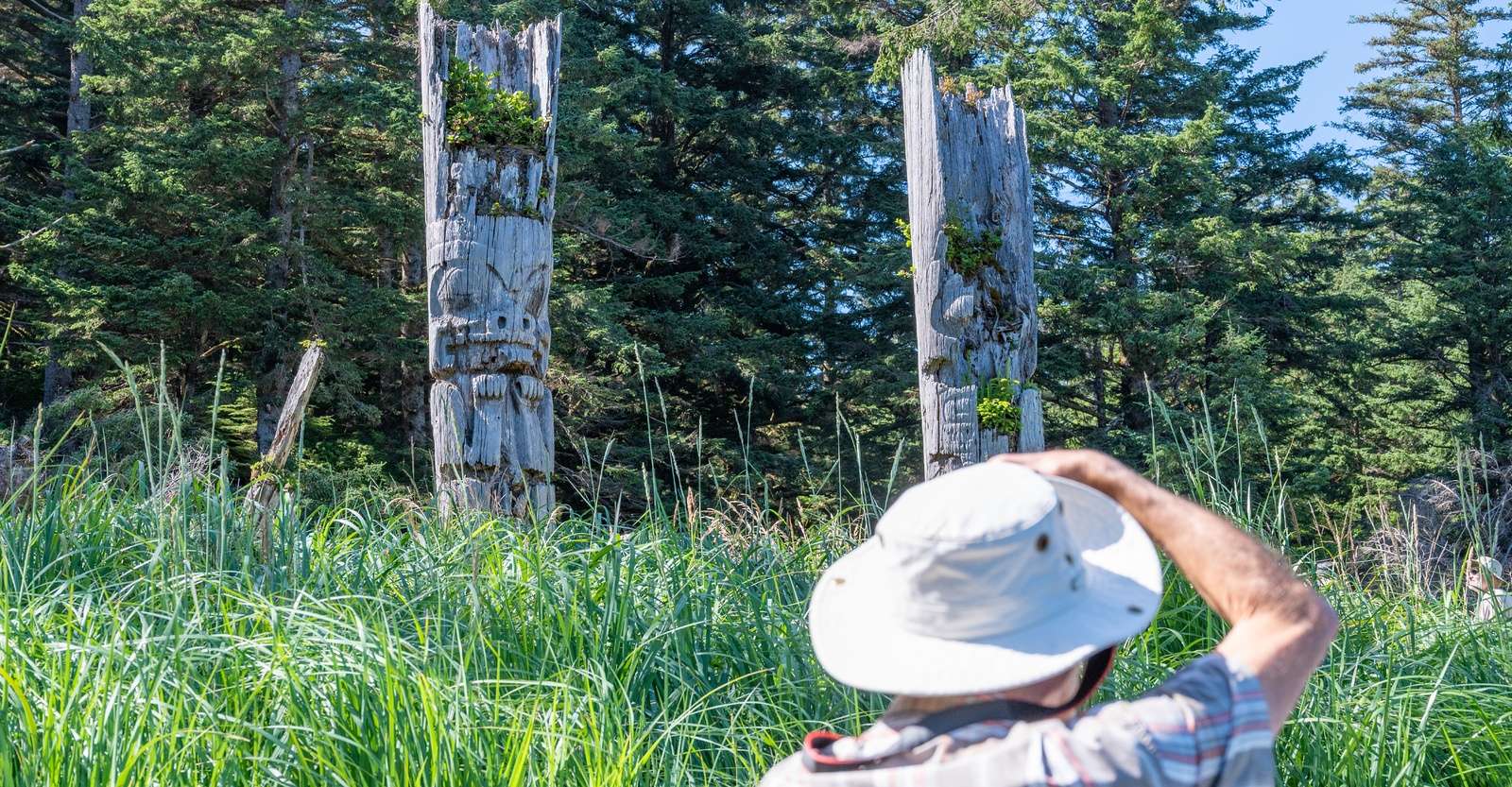 Nat Hab guest photographing totem poles, Haida Gwaii, British Columbia.