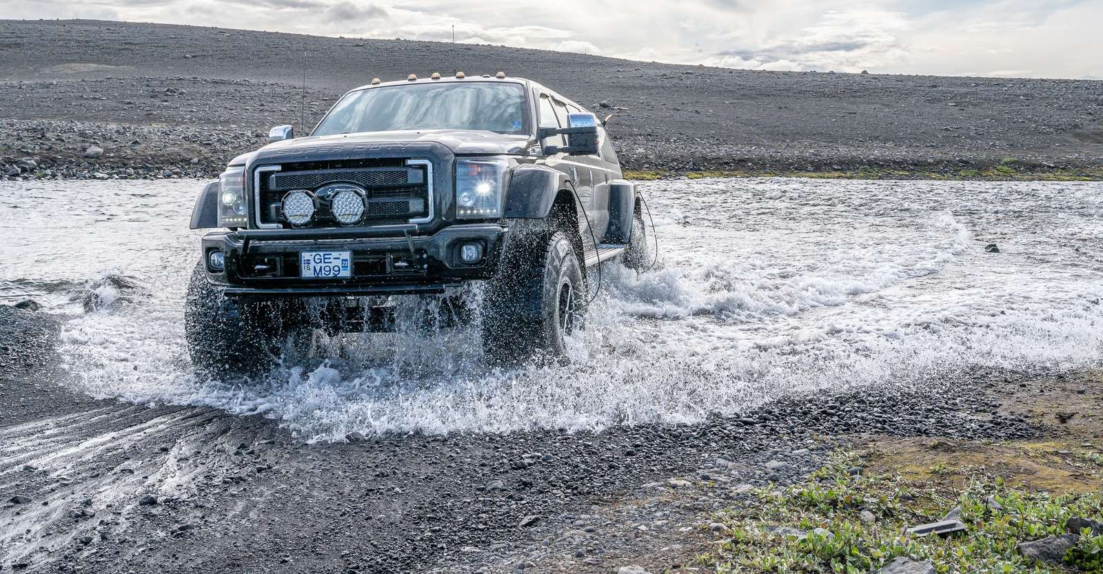 4x4 vehicle fording glacial river, Iceland.