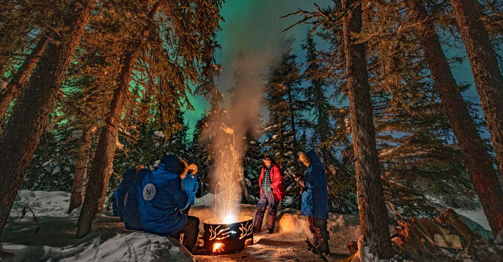 Nat Hab guests around campfire viewing the northern lights, Churchill, Manitoba.