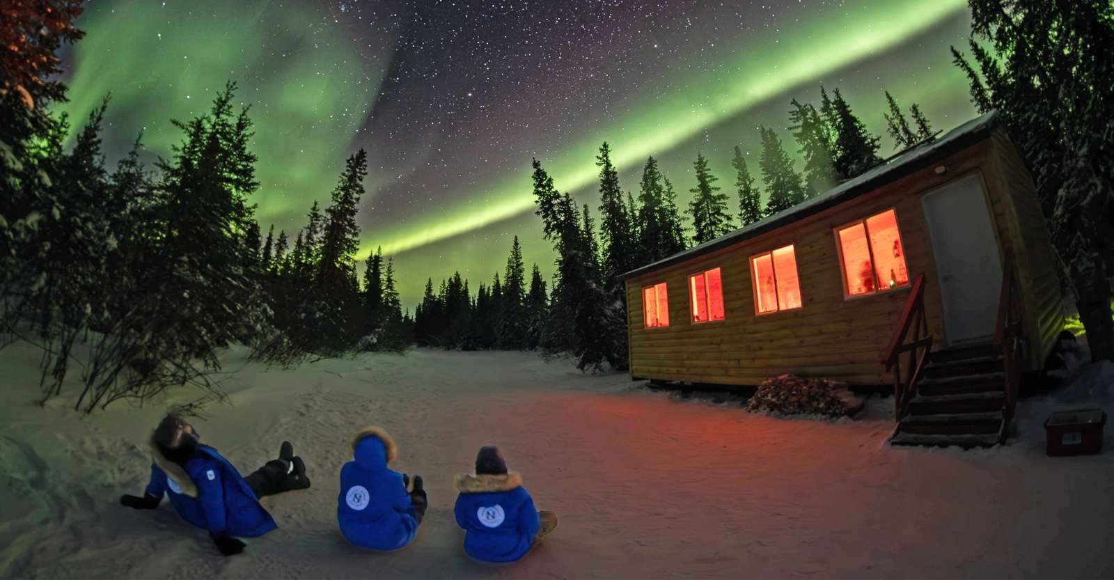 Nat Hab guests next to cabin viewing the northern lights, Churchill, Manitoba.